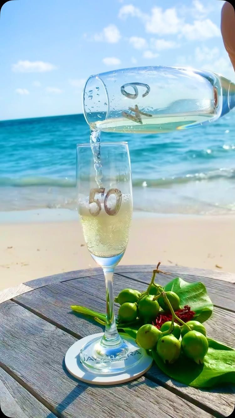 Champagne pouring into a glass with number 50 on a tropical beach