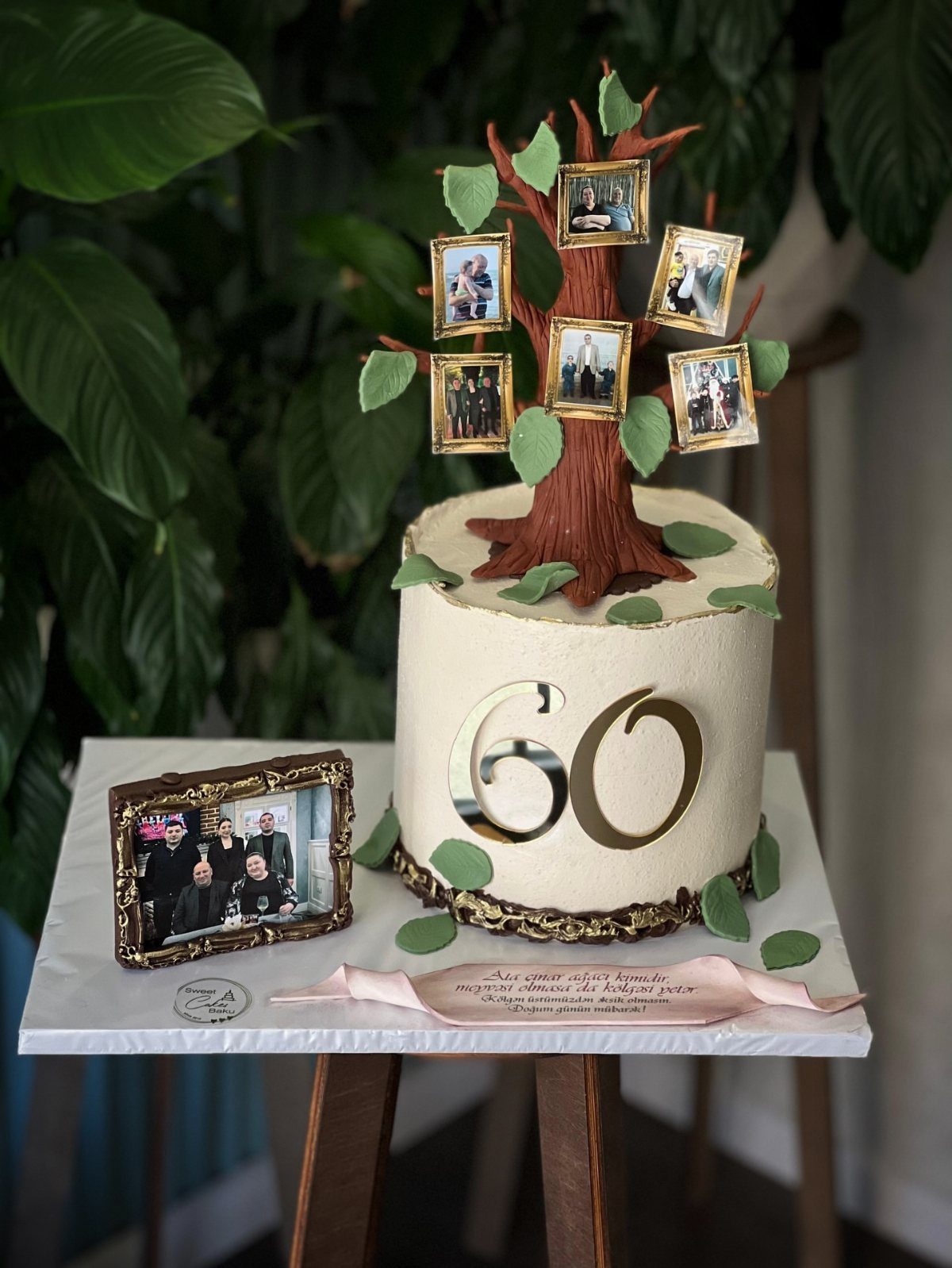 White birthday cake with a 60 topper and a tree of family photos.