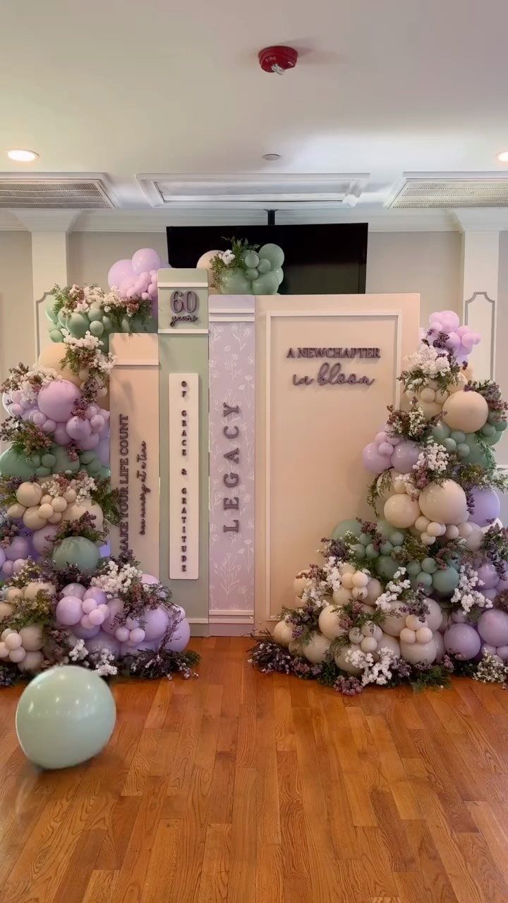Event backdrop with giant books, balloons, and flowers for a 60th birthday celebration.