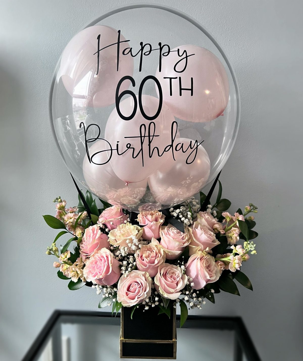 Pink rose bouquet with a large clear 60th birthday balloon on top.