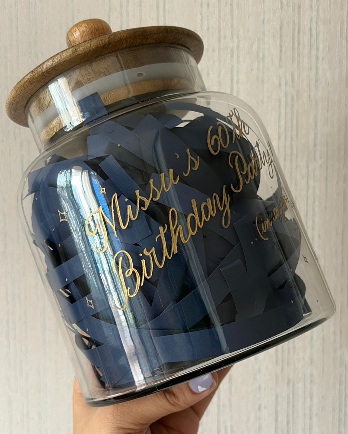 Glass jar with wooden lid filled with blue notes for 60th birthday