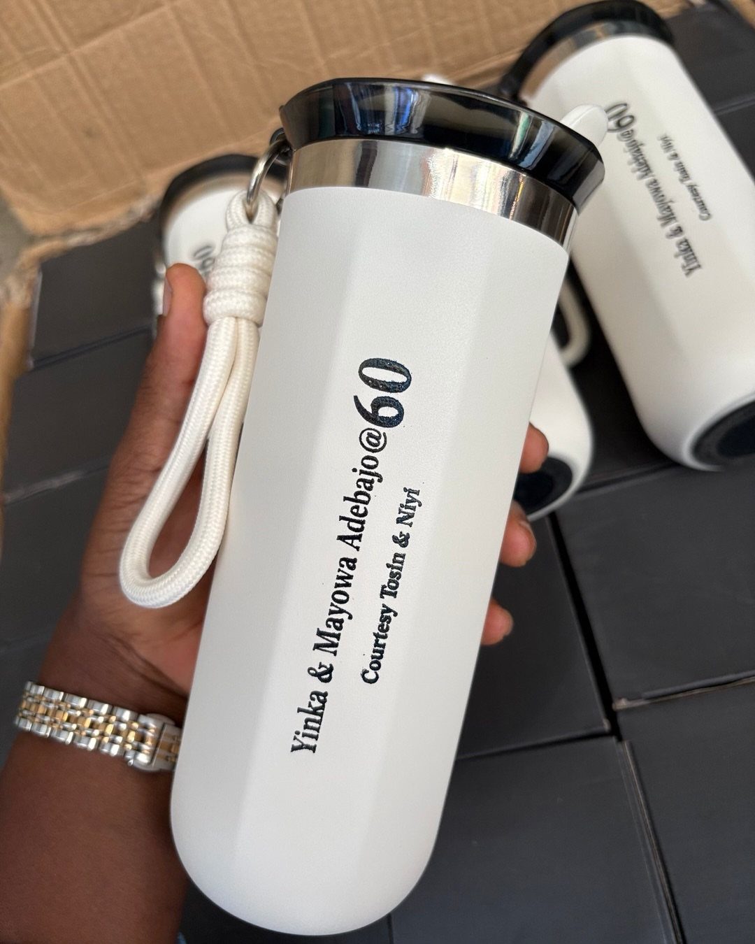 White insulated water bottle with personalized 60th birthday text held by a hand