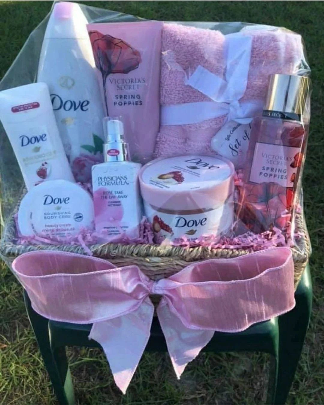 Wicker gift basket filled with pink beauty products and a towel wrapped in cellophane.