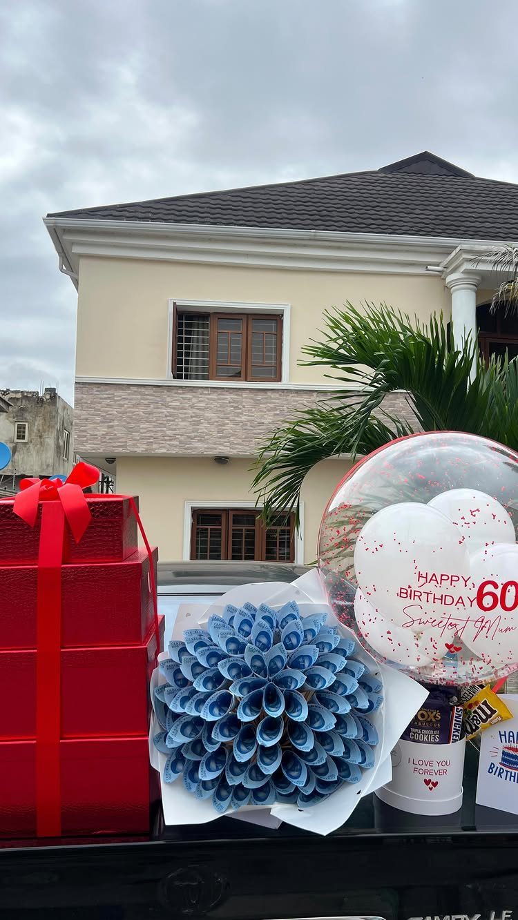 Red gift box, blue money bouquet, and 60th birthday balloon outdoors.