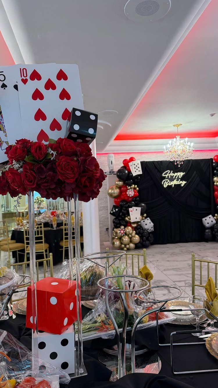 Casino themed birthday party decorations with giant dice, playing cards, and red roses.