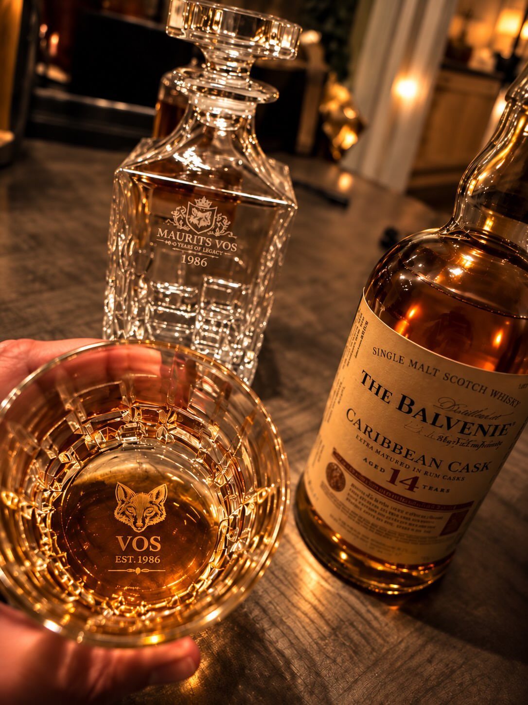 Engraved crystal whiskey glass and decanter set next to a scotch bottle.