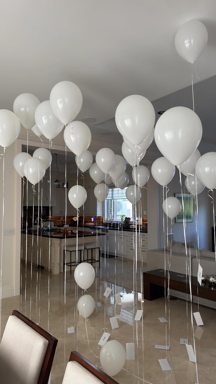 White balloons floating in a living room with small cards attached to strings