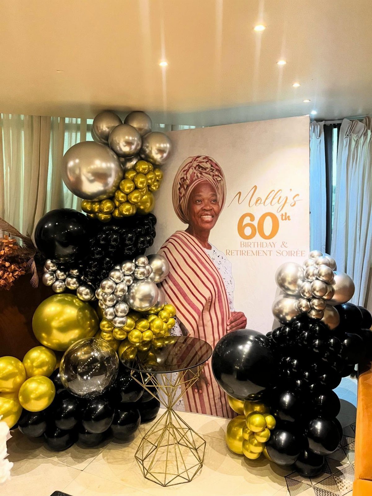Celebration backdrop with gold and black balloons and a 60th birthday banner.