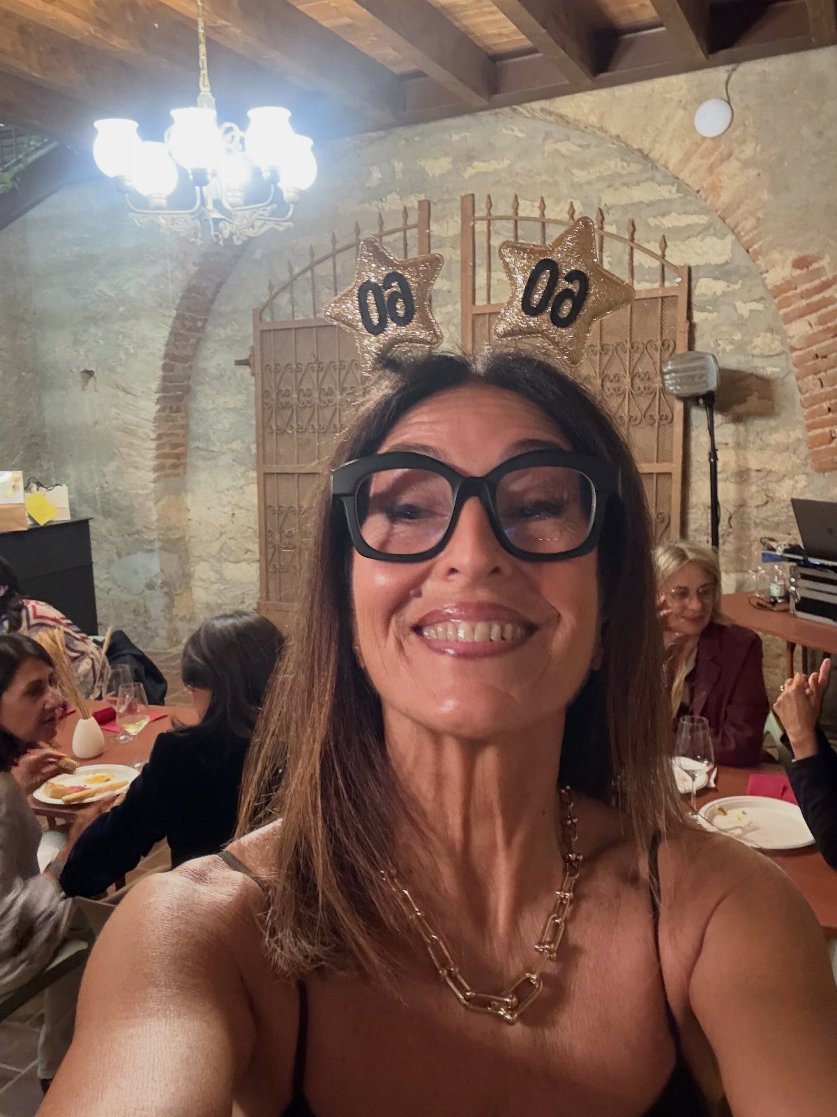 Woman wearing 60th birthday star headband smiling at a celebratory dinner party.
