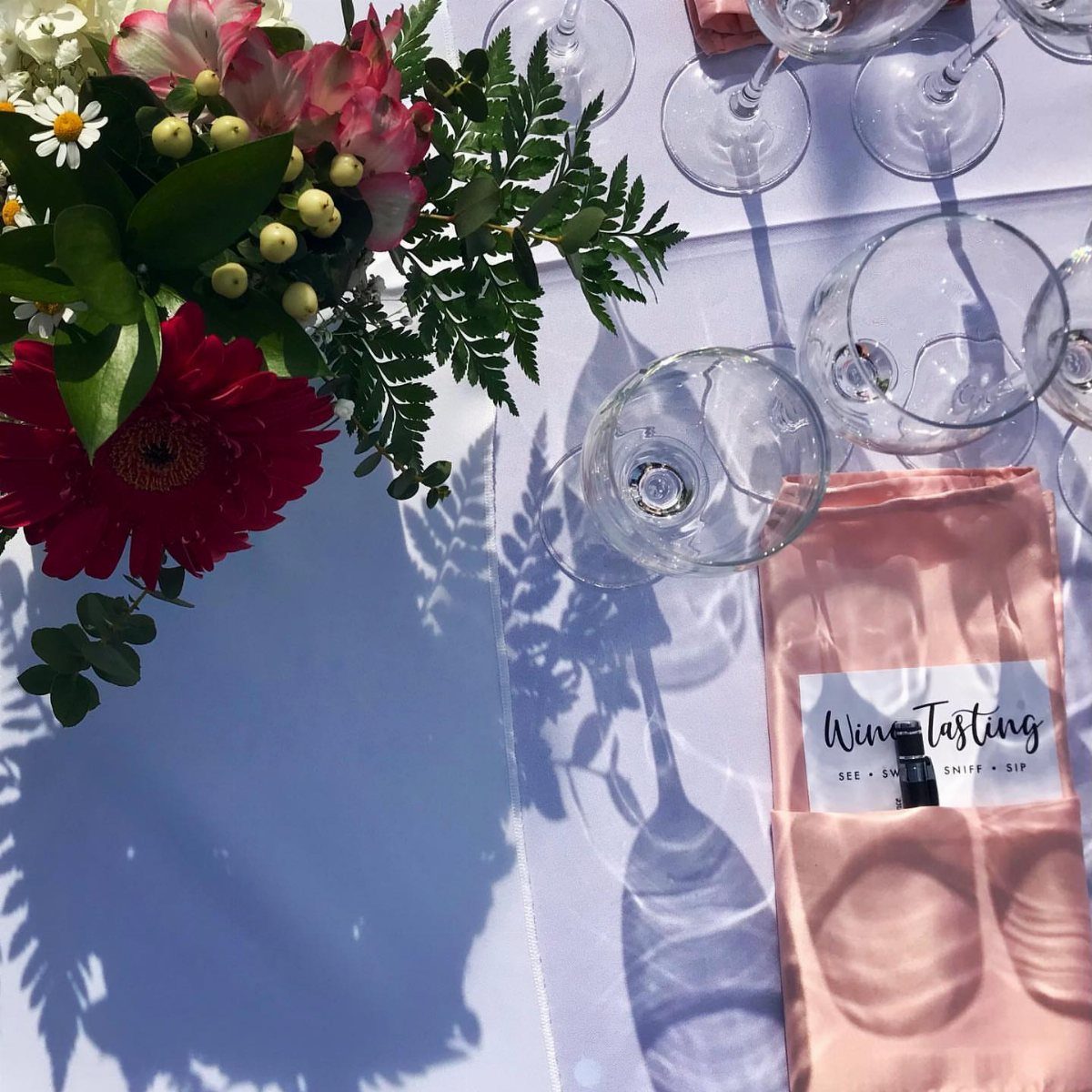Wine glasses and a floral bouquet next to a wine tasting kit.