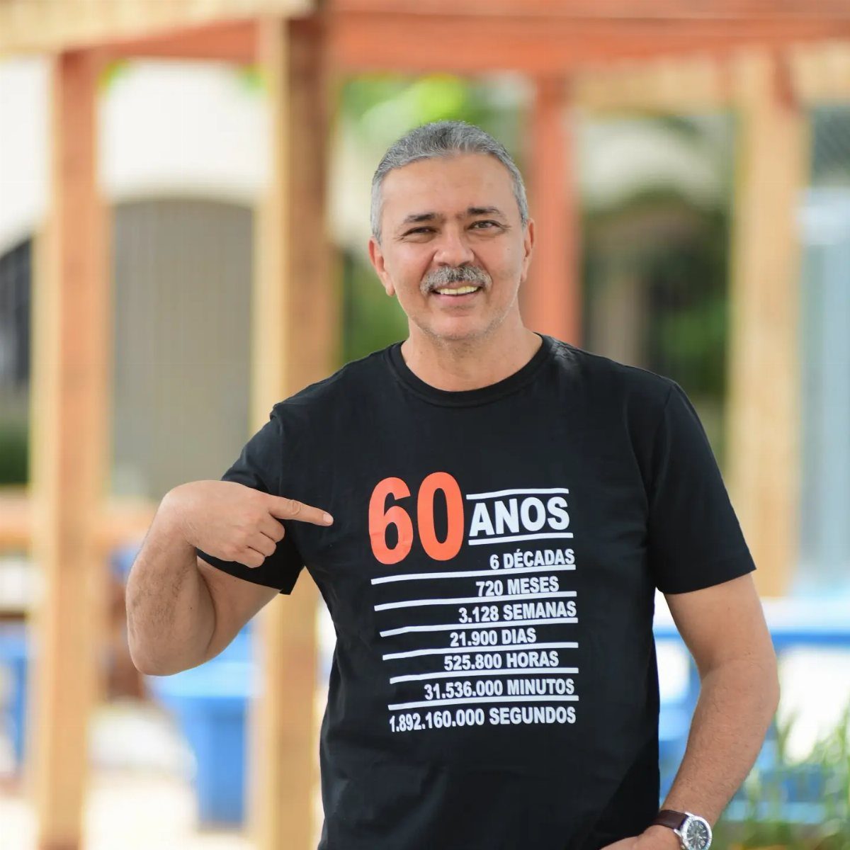 Man wearing a black 60th birthday t-shirt with age breakdown in Portuguese