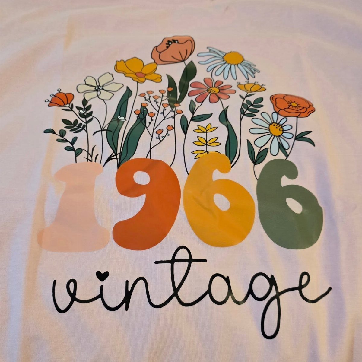 White t-shirt with colorful flowers, the year 1966, and the word vintage.