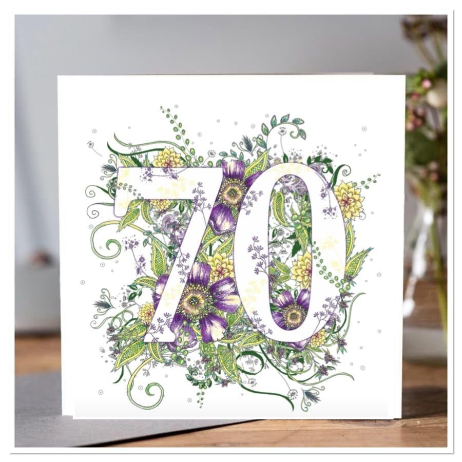 White birthday card with the number 70 filled with purple and yellow flowers.