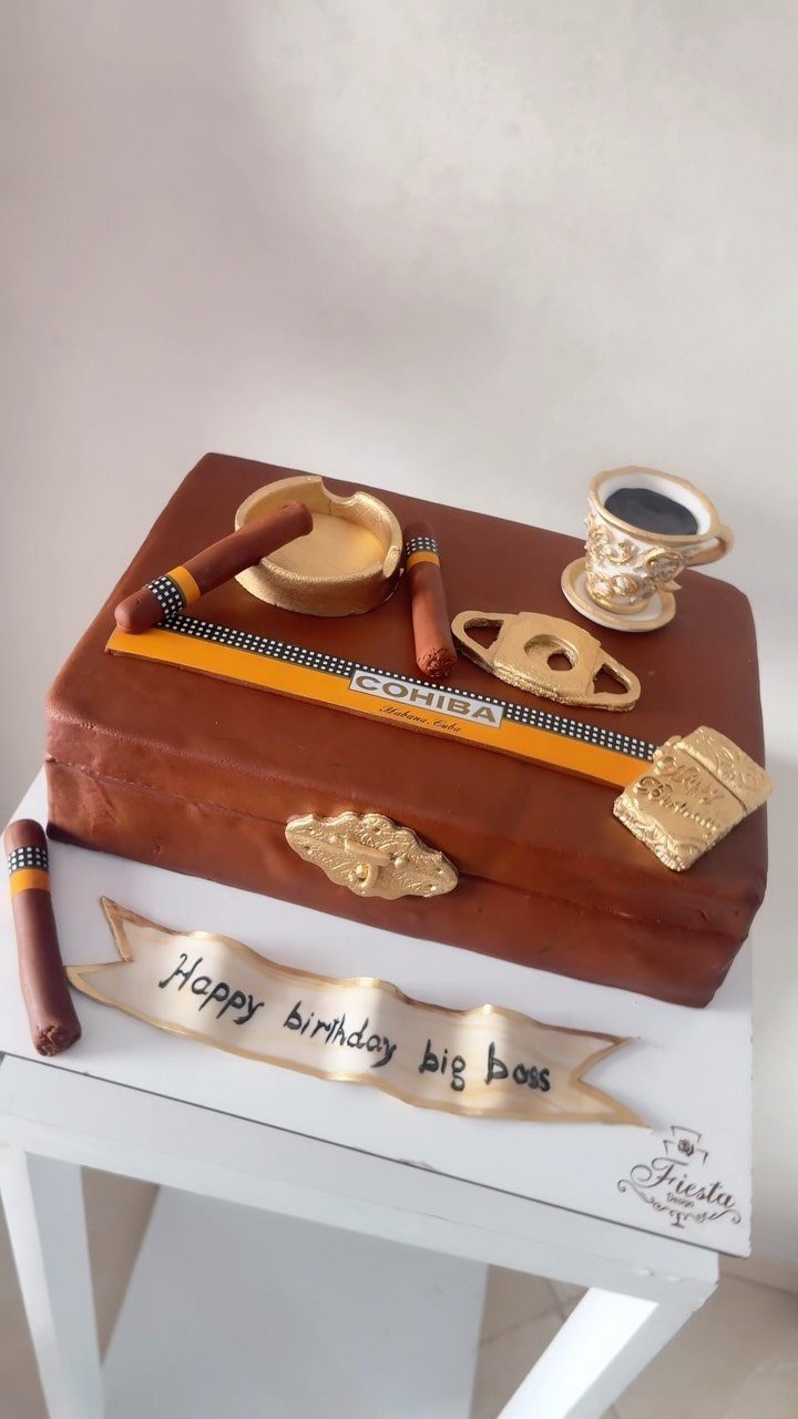 Briefcase-shaped birthday cake with edible cigars, gold watch, and coffee cup decorations.
