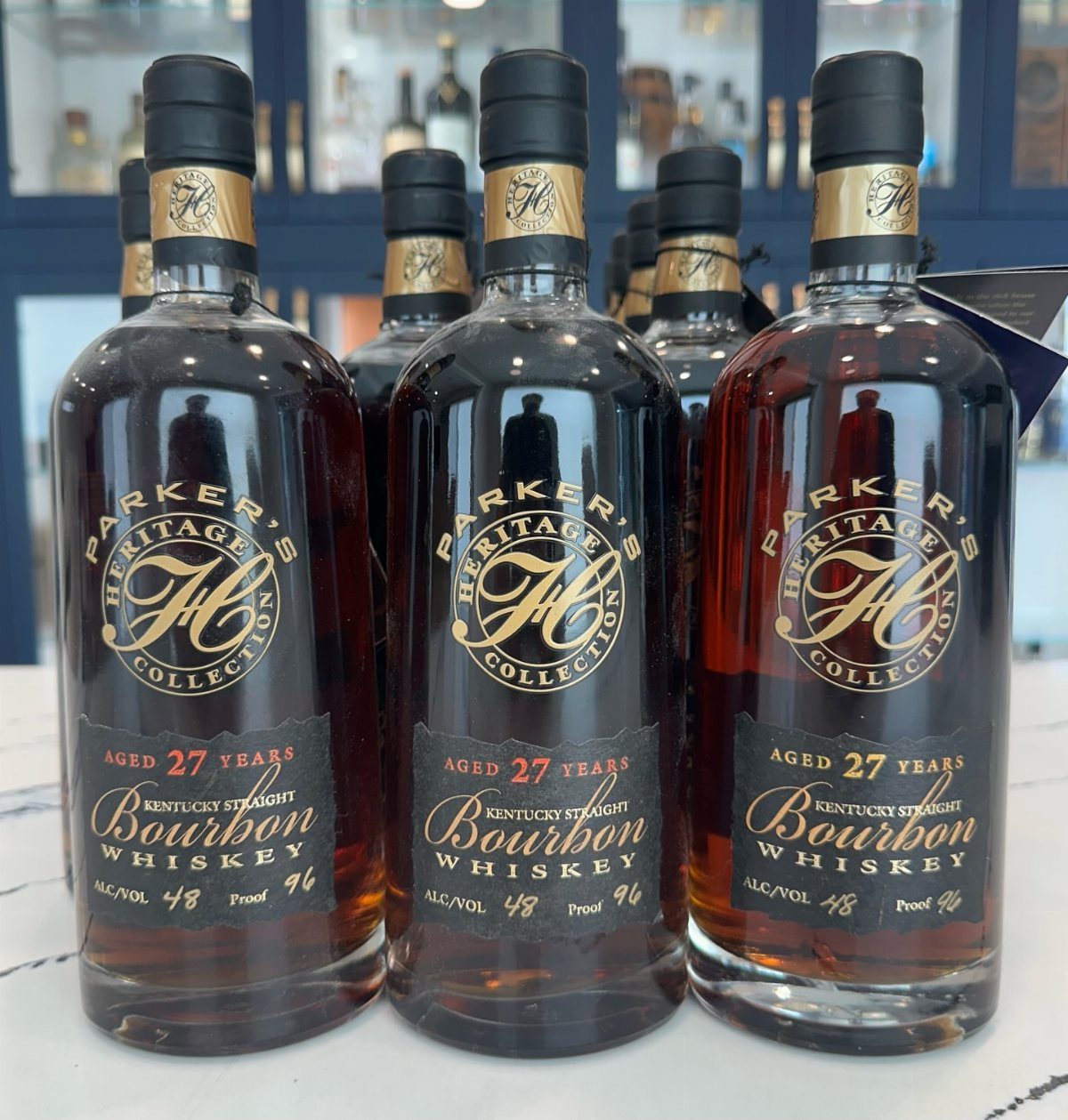 Three bottles of aged bourbon whiskey with gold labels on a white surface.