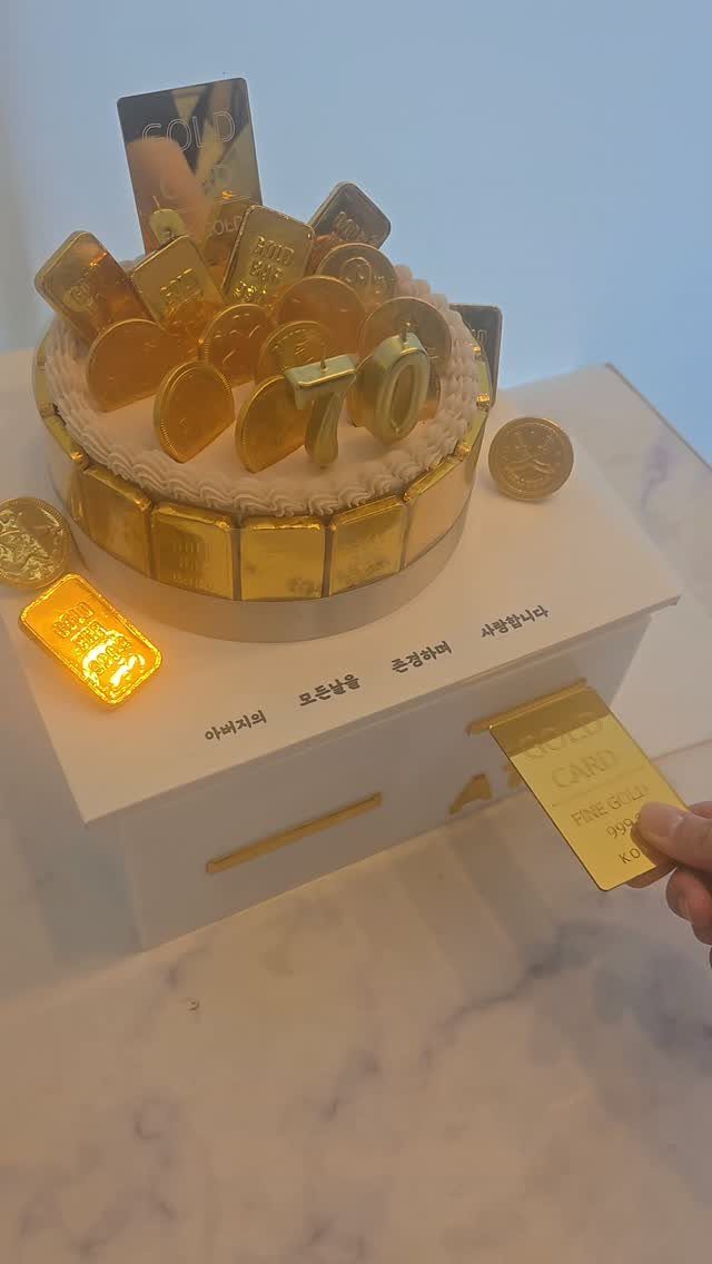 Gold bar and coin themed cake with a number 70 topper on white base