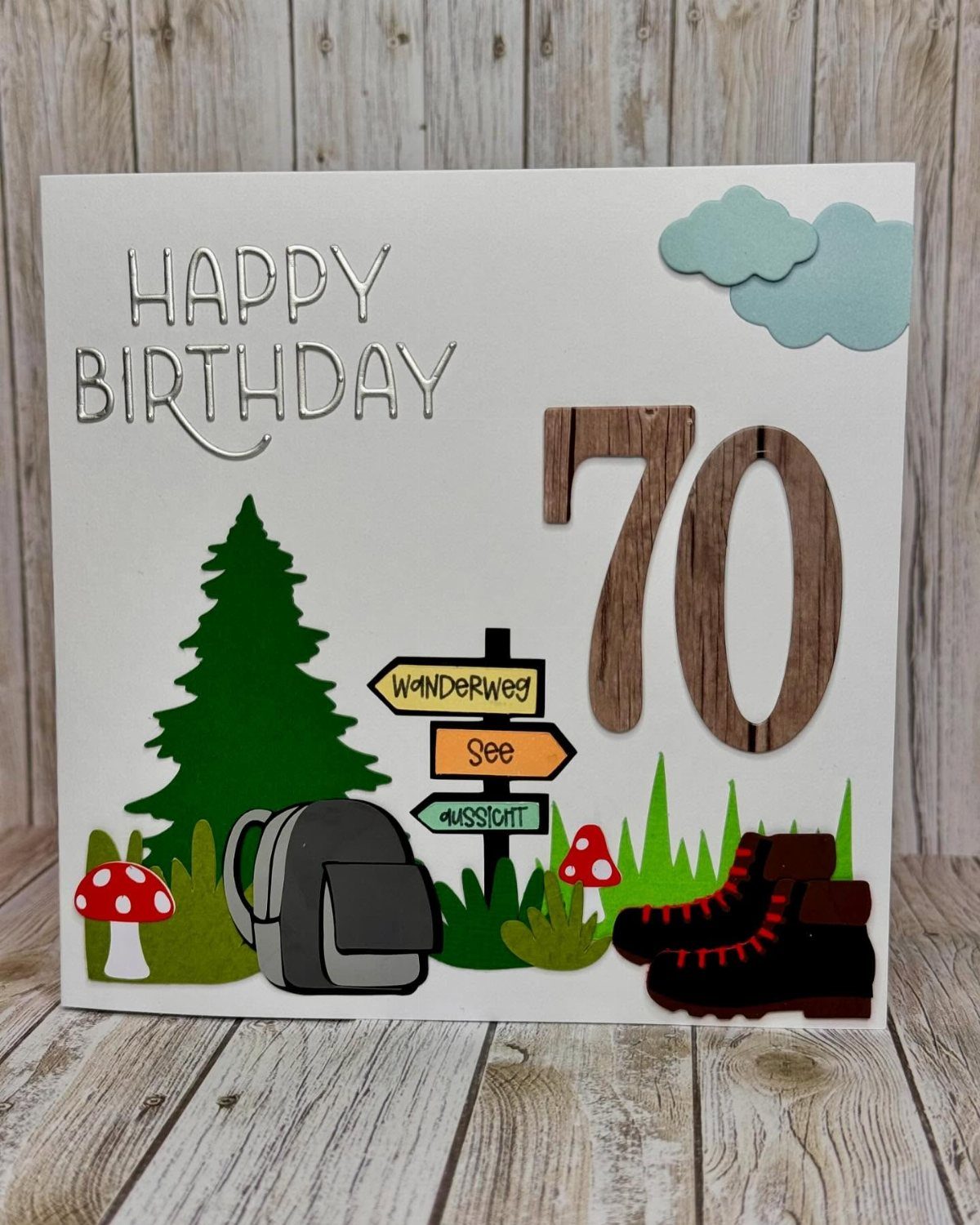 Handmade 70th birthday card with hiking theme, featuring boots, backpack, and pine tree.