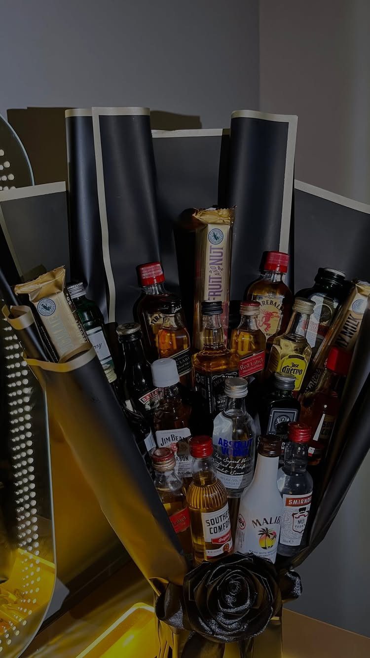 Miniature liquor bottles and snacks arranged in a black and gold gift bouquet.