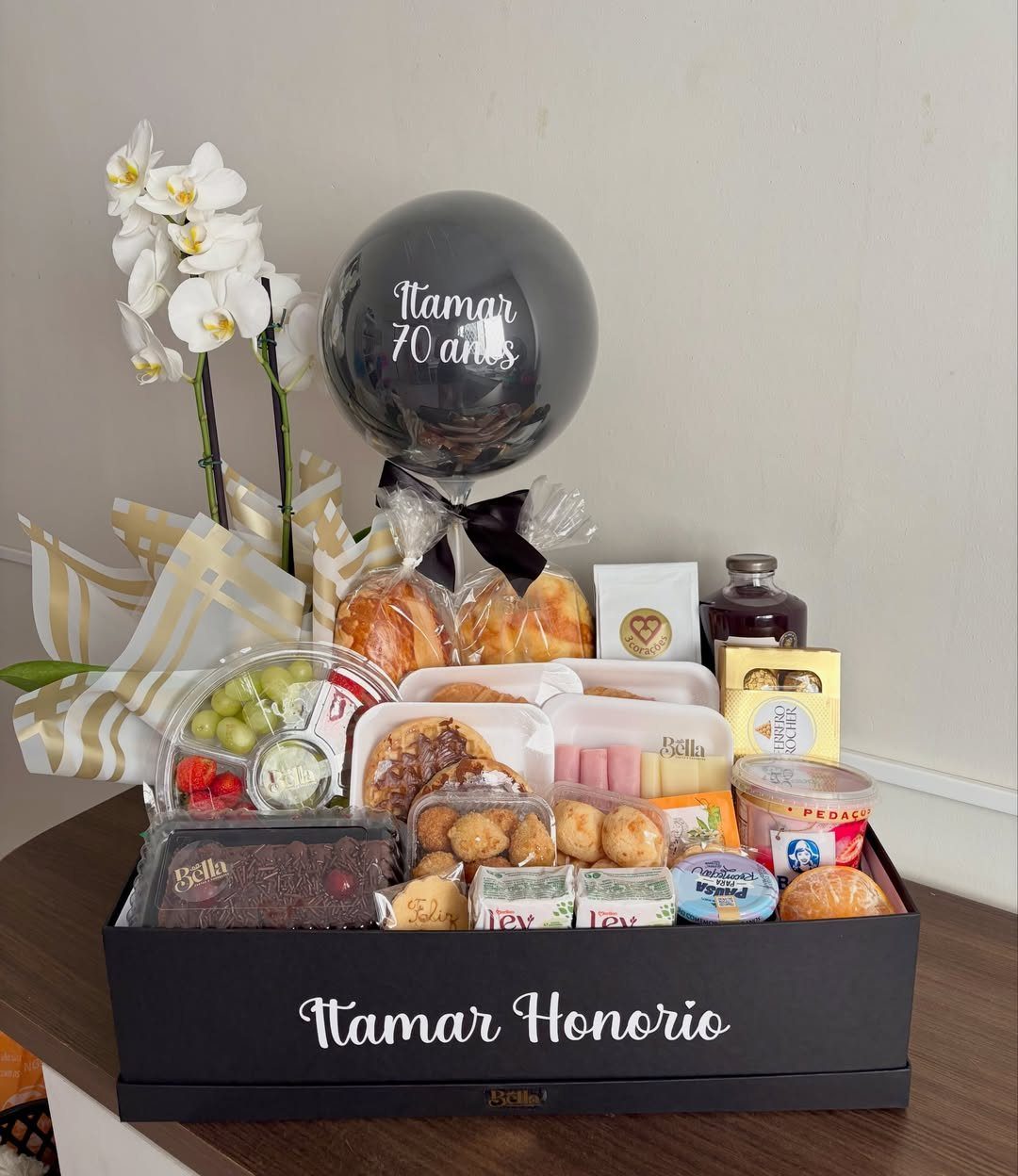 Gourmet food hamper in a black box with a 70th birthday balloon and orchids.