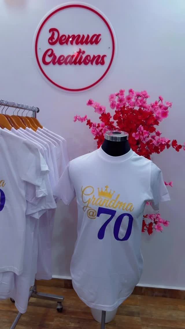 White t-shirt on a mannequin with Grandma @ 70 printed in purple and gold.