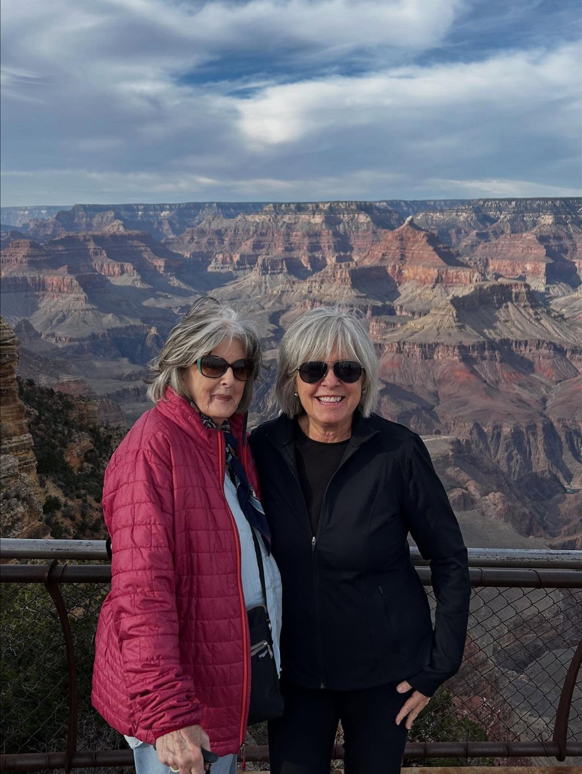 Two senior women smiling in front of the Grand Canyon landscape.