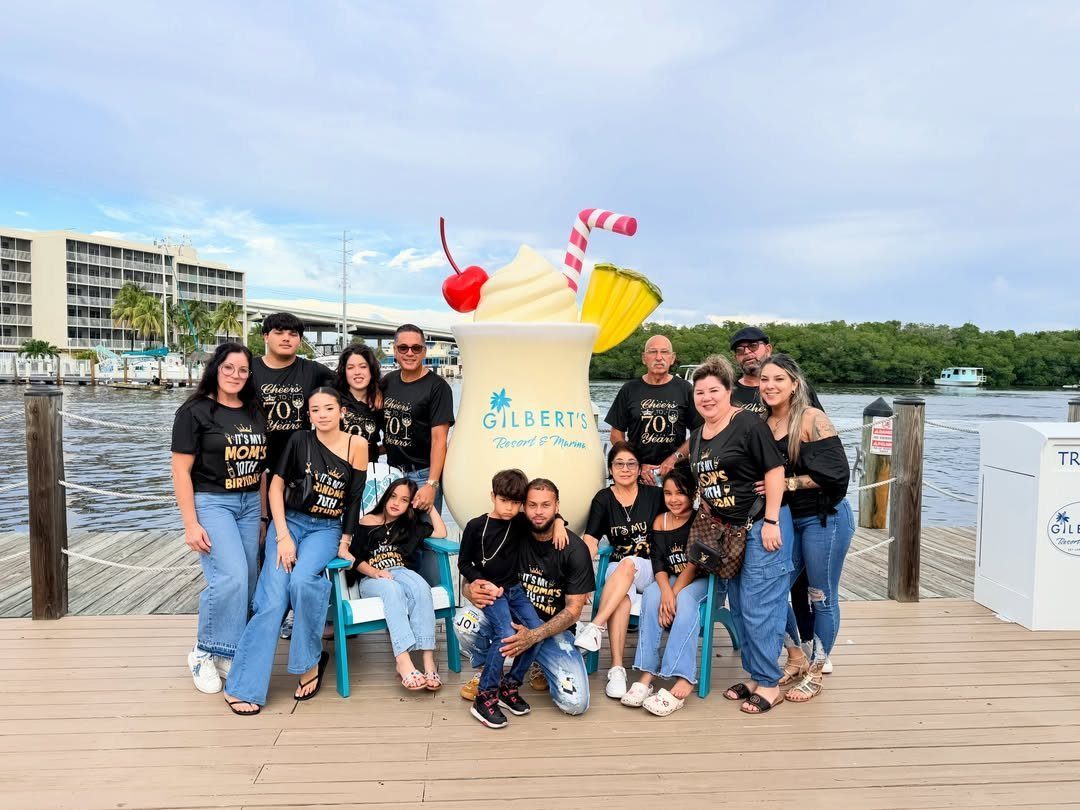 Family group in matching black shirts posing by a giant tropical drink sculpture.