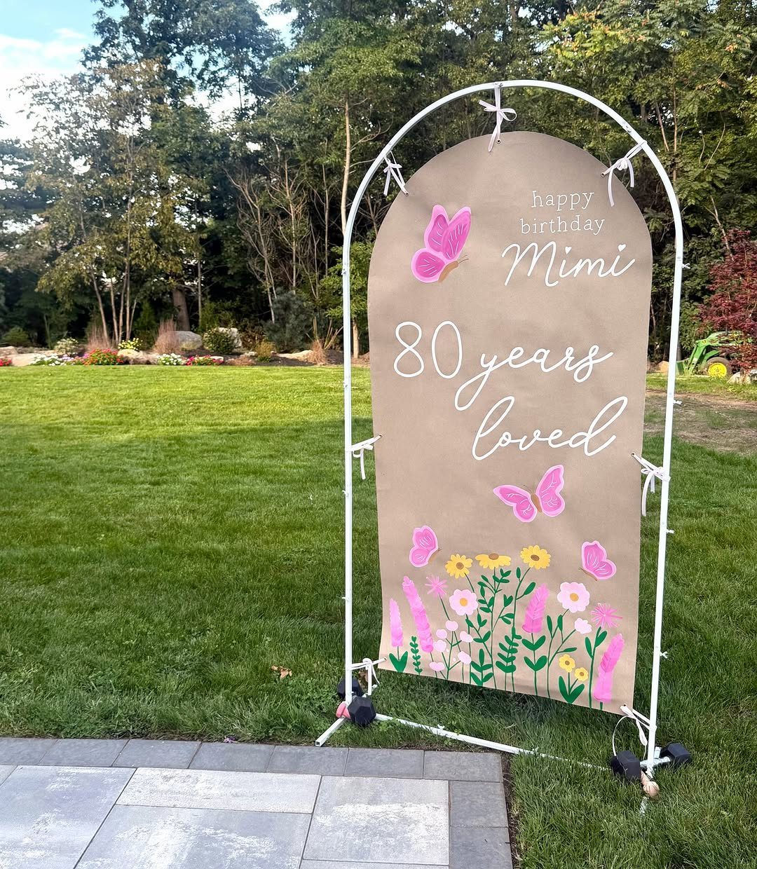 Arched birthday backdrop with pink butterflies and flowers for Mimi's 80th birthday.