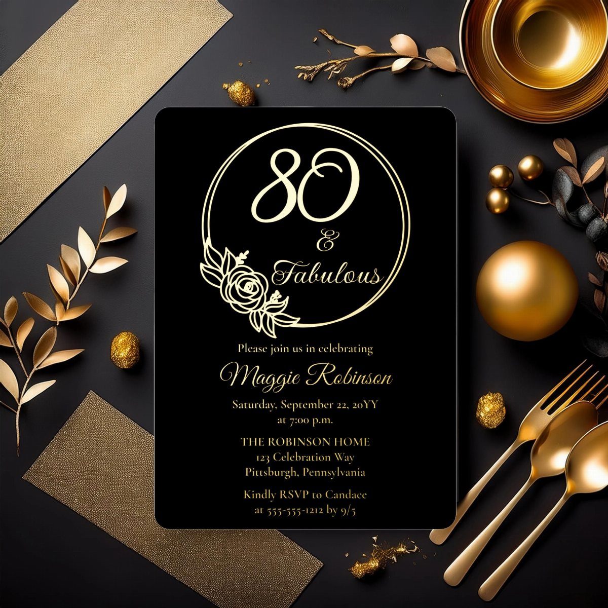Black 80th birthday invitation with gold foil lettering surrounded by gold decorative objects.