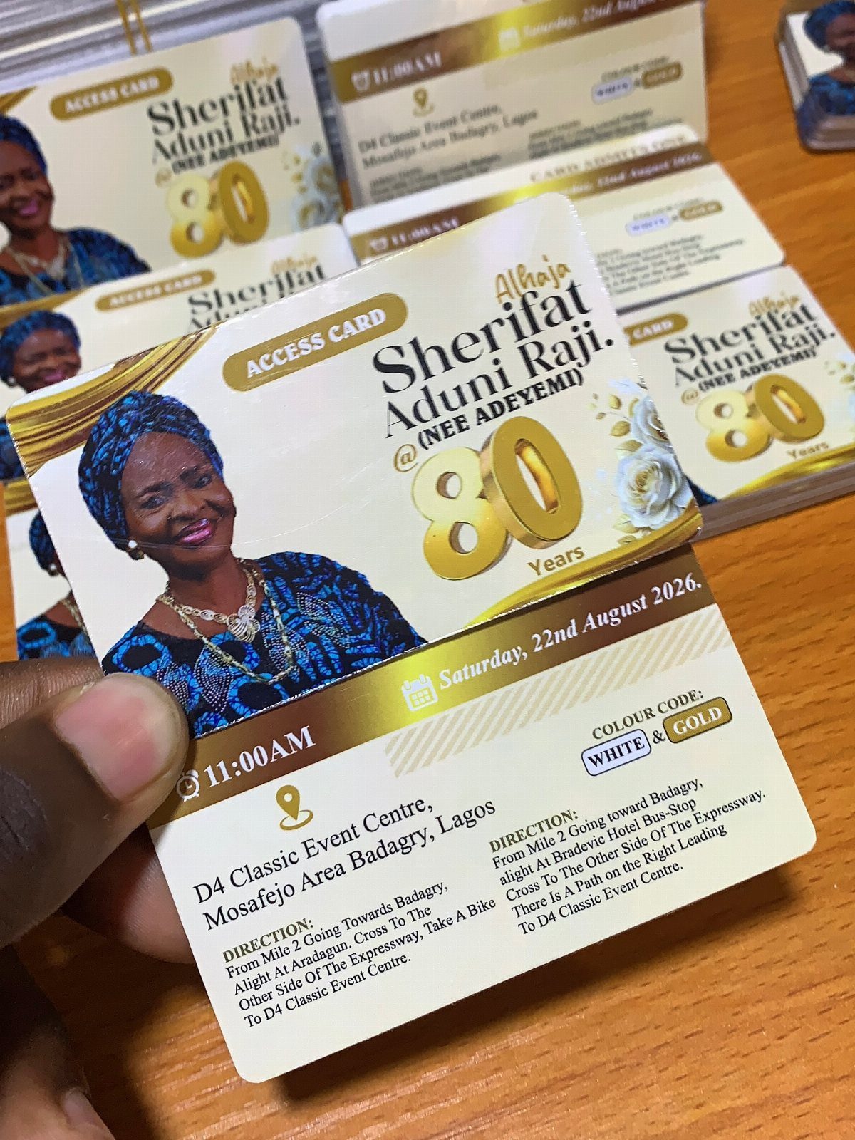 Gold and white 80th birthday invitation card featuring a woman's portrait and event details.