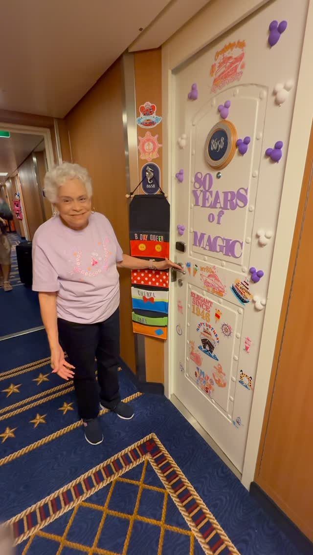 Elderly woman standing by a cruise ship door decorated for her 80th birthday.