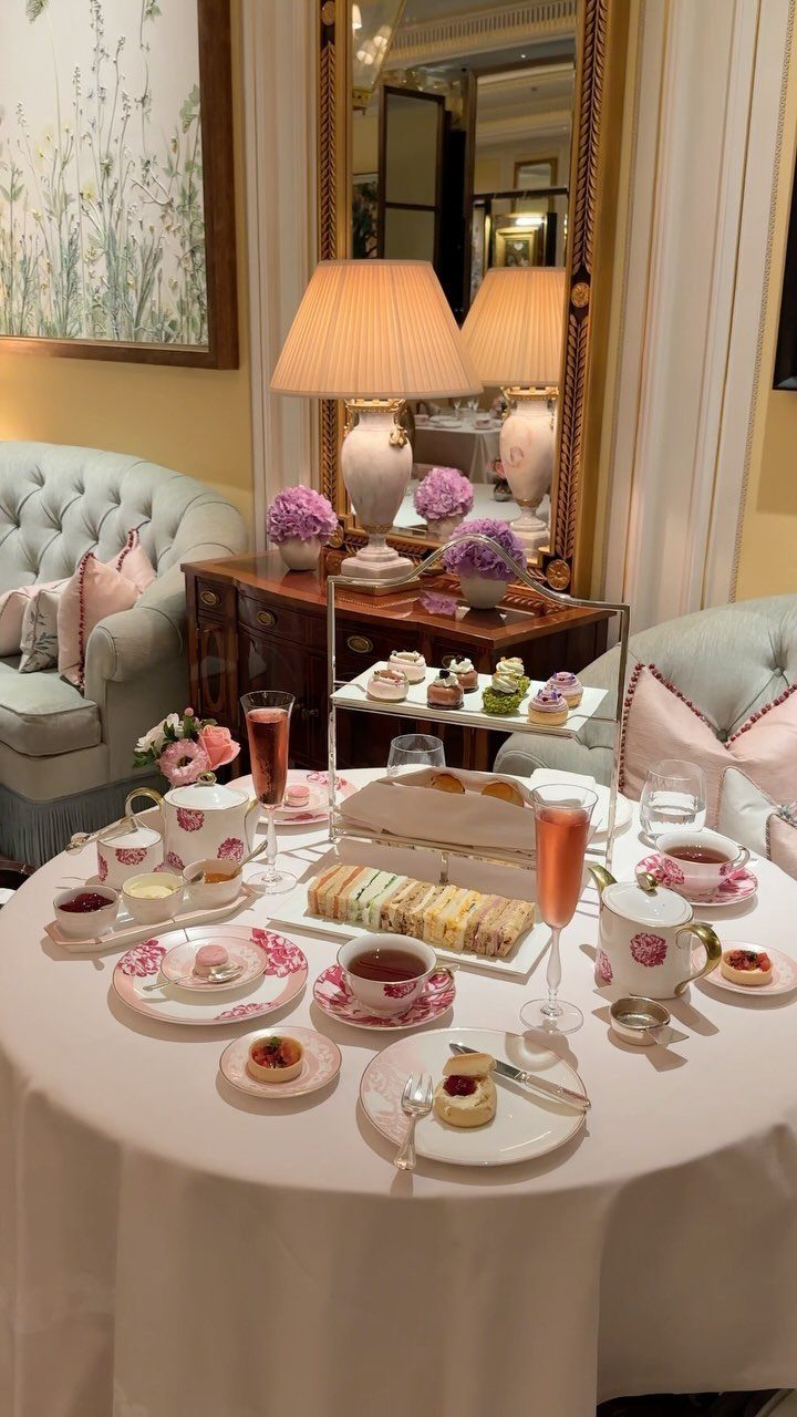 Afternoon tea spread with tiered cakes, sandwiches, and champagne in a luxury room.