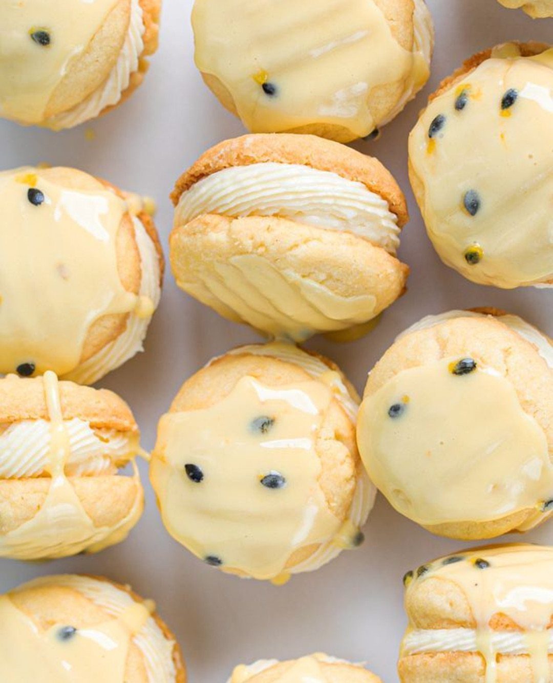 Cream puffs with white filling and yellow glaze topped with dark seeds.