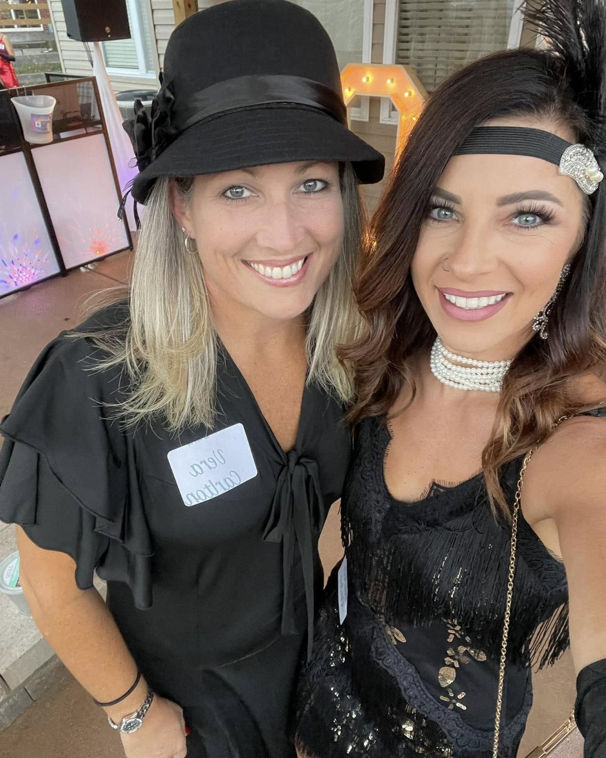 Two women in 1920s flapper costumes smiling at a themed birthday party.