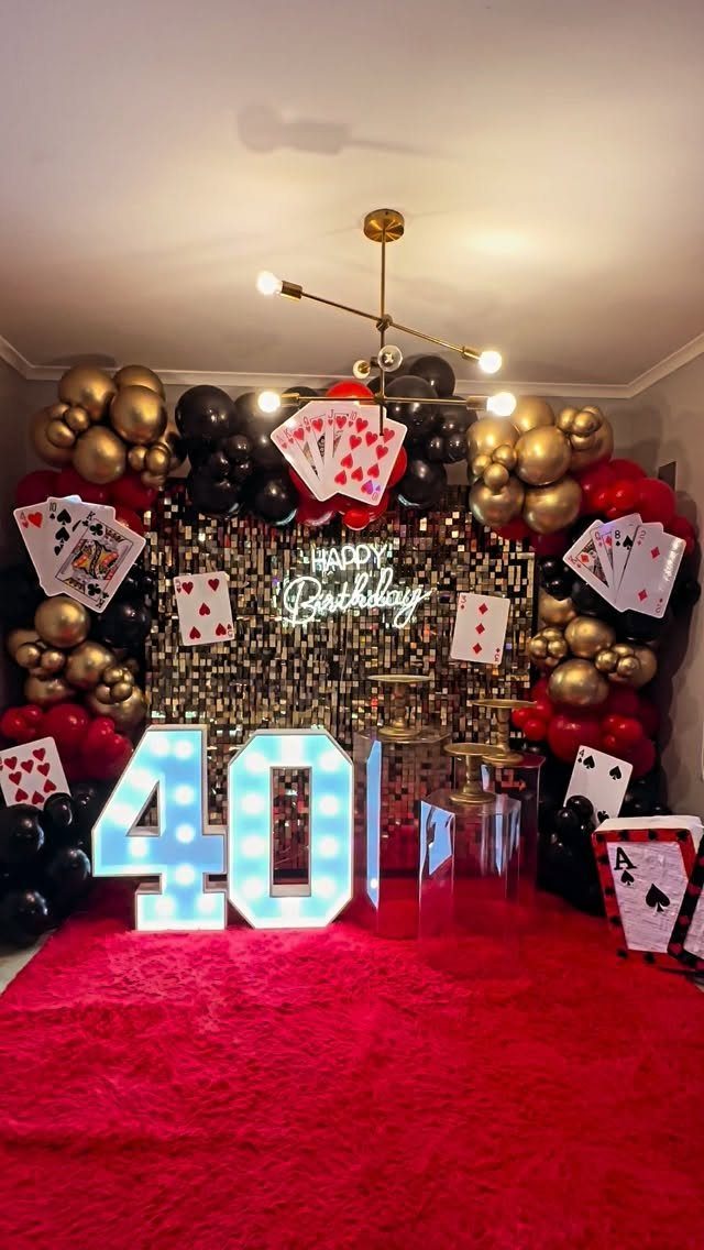 40th birthday party decorations with red carpet, gold tinsel, and giant playing cards.