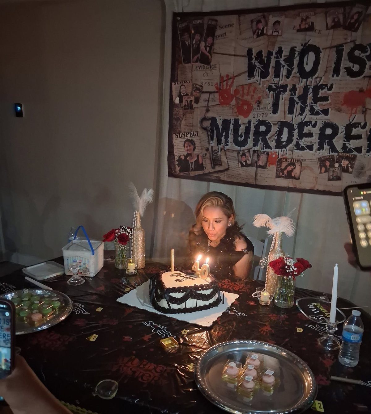 Woman at a birthday table with a Who Is The Murderer crime banner
