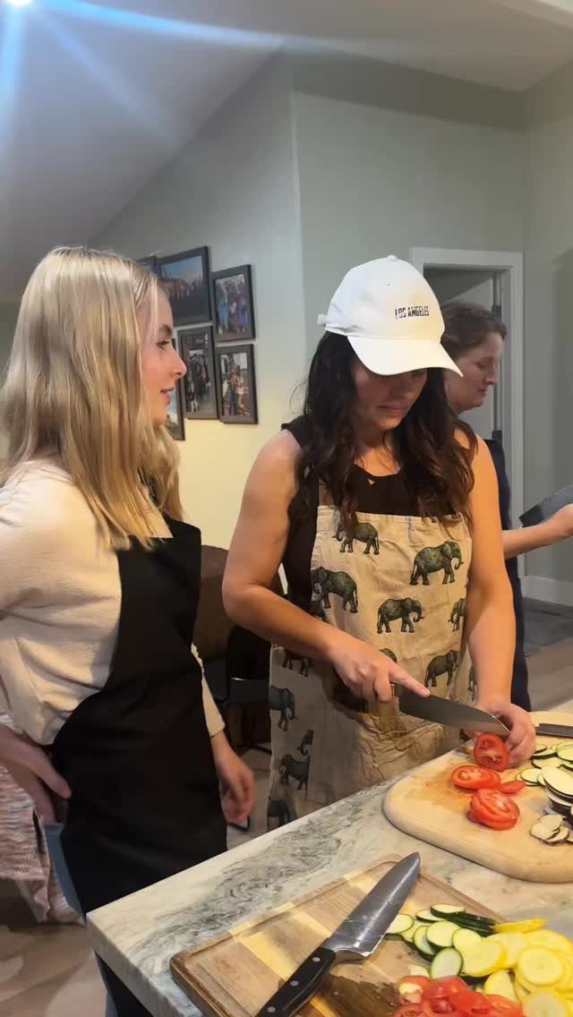 Women preparing fresh vegetables in a kitchen during a cooking activity.