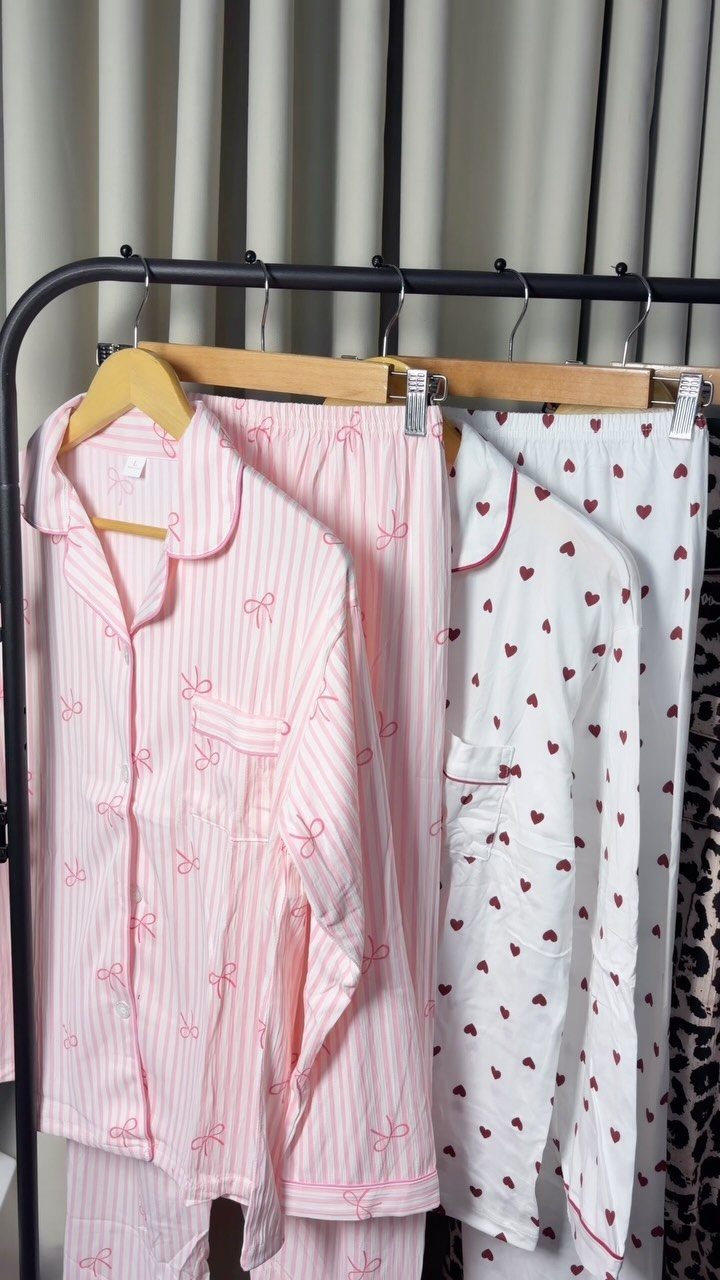 Pink striped and white heart-patterned pajama sets hanging on a black clothing rack.