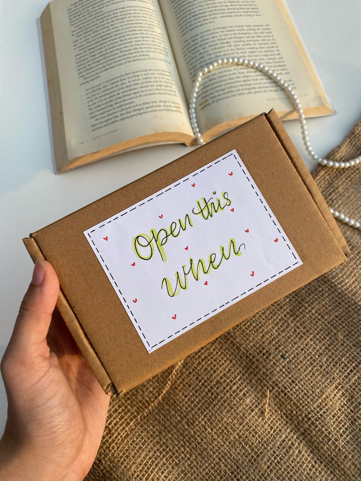 Brown cardboard gift box with 'Open this when' label held by a hand.