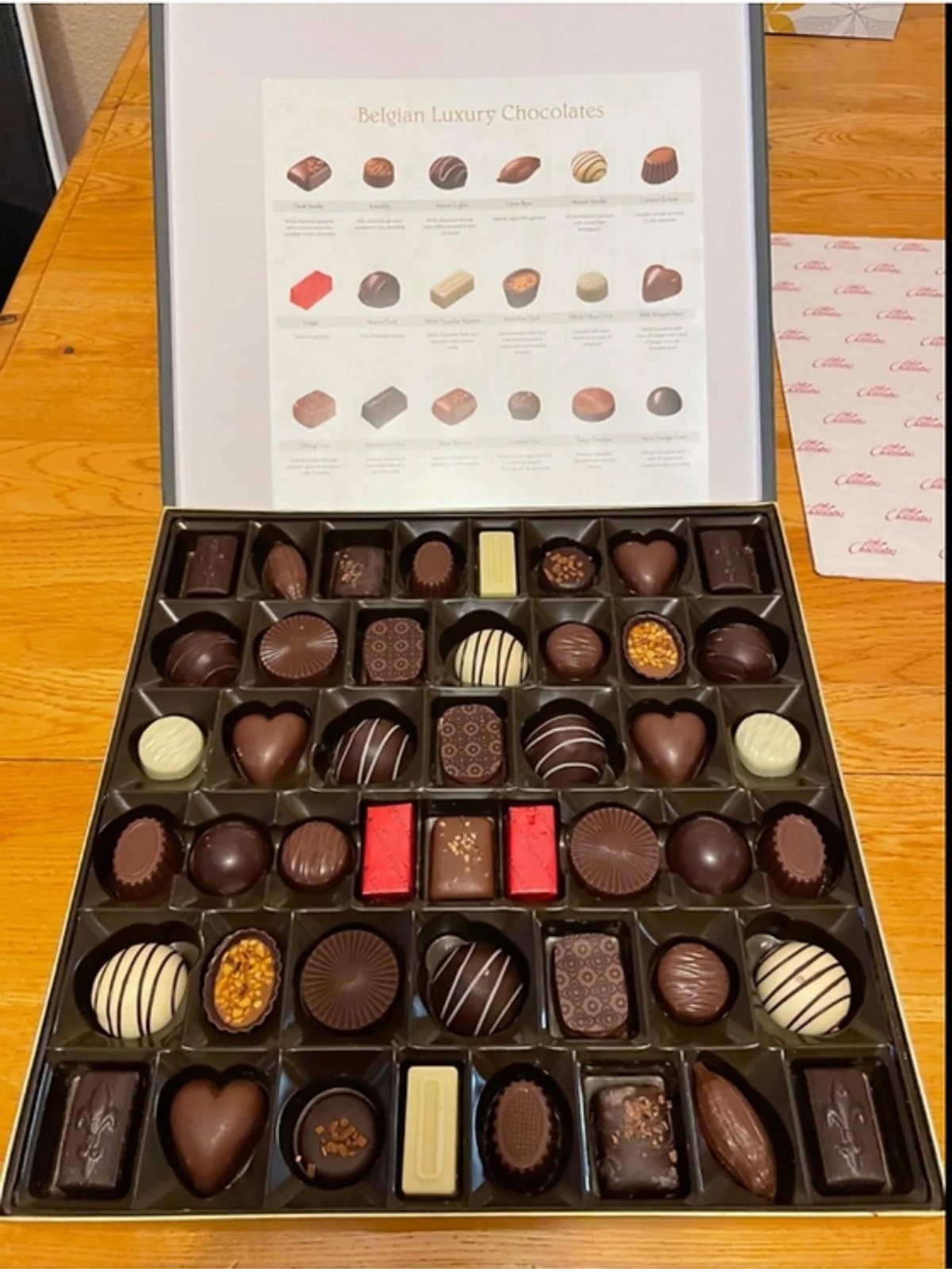 Assorted Belgian luxury chocolates in a gift box with a descriptive guide lid.