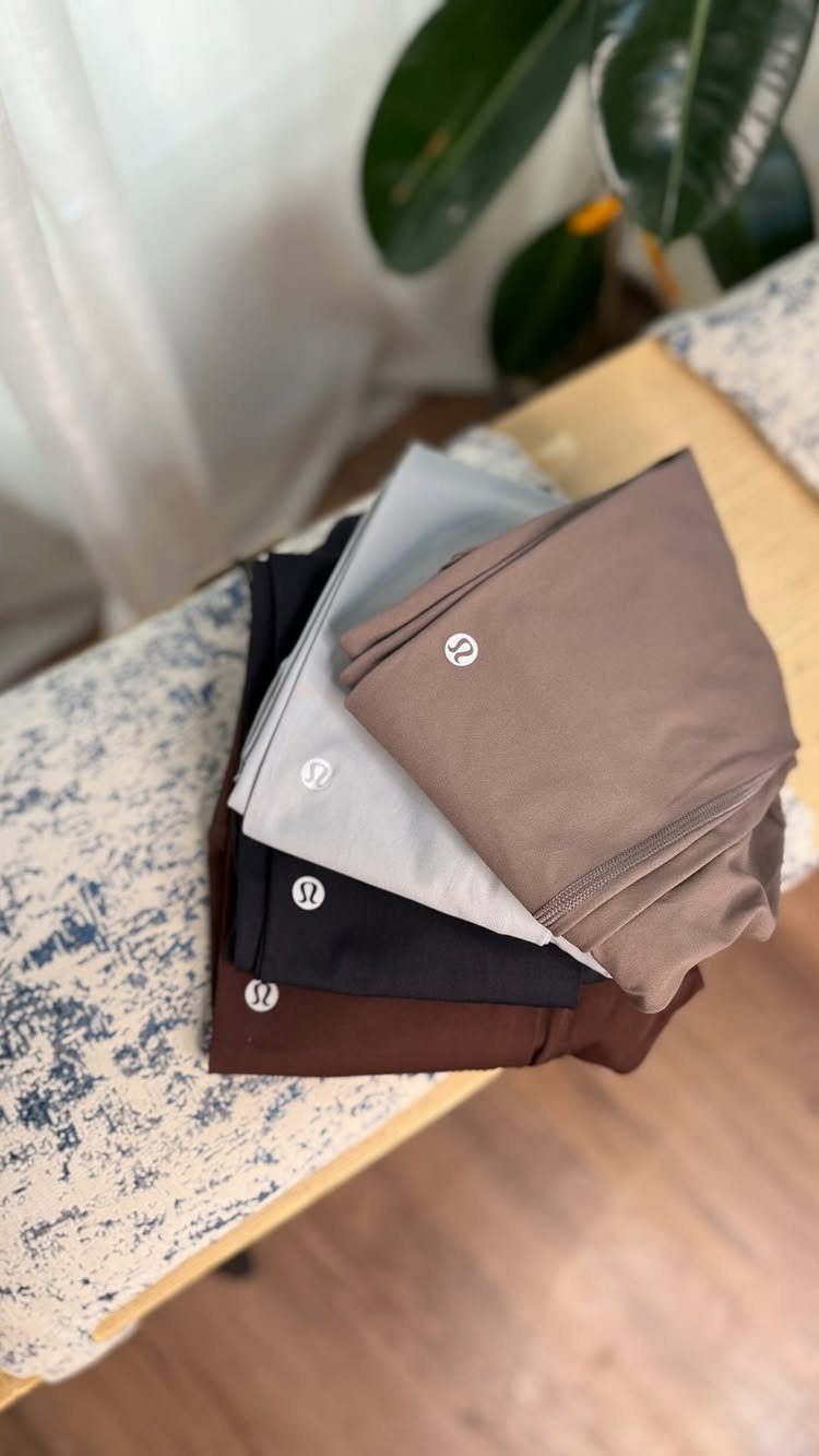 Folded athletic leggings in neutral colors stacked on a patterned surface.