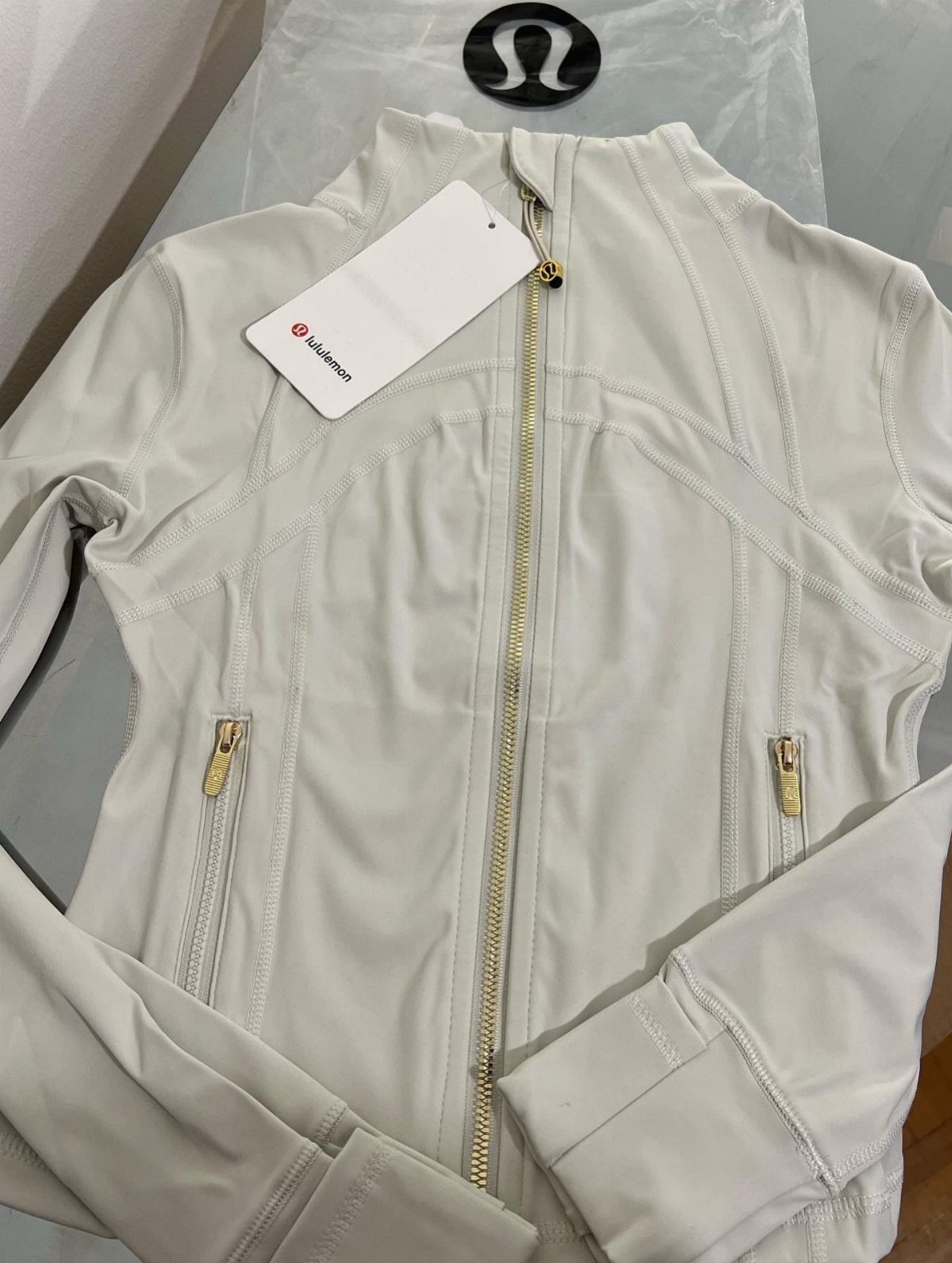 White Lululemon zip-up athletic jacket with gold zippers and a brand logo.