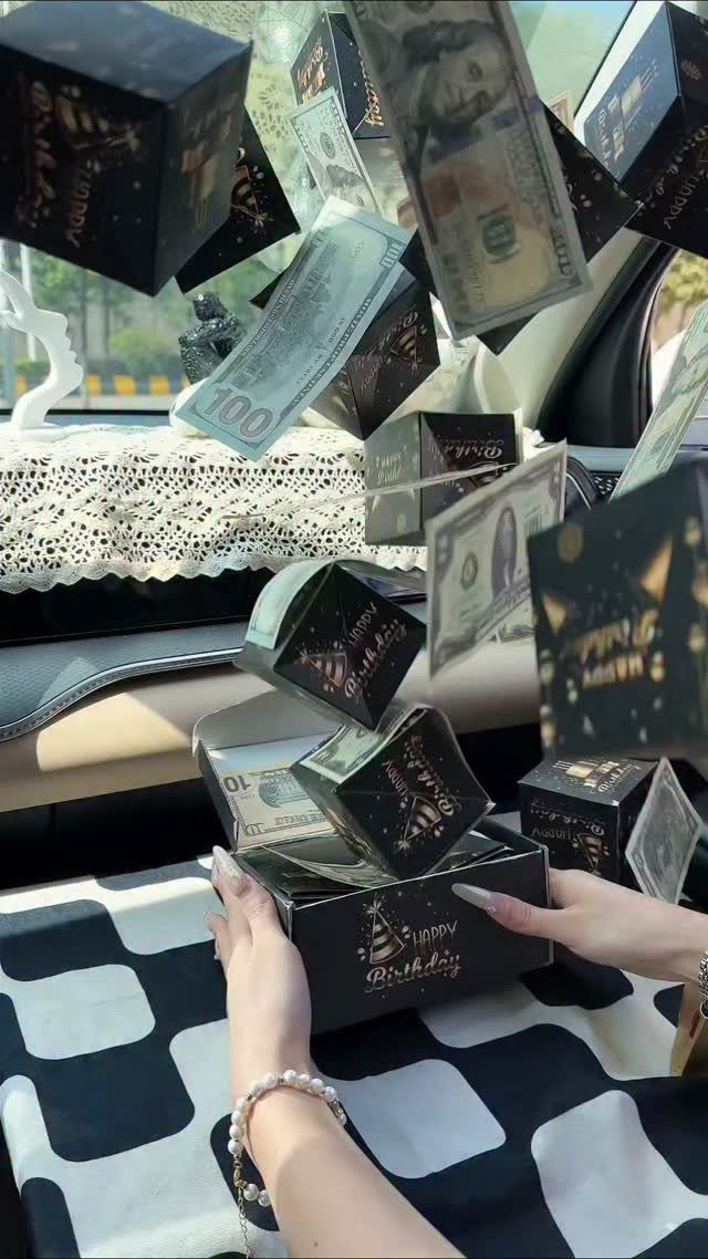 Hands holding a black gift box with floating money and small boxes.