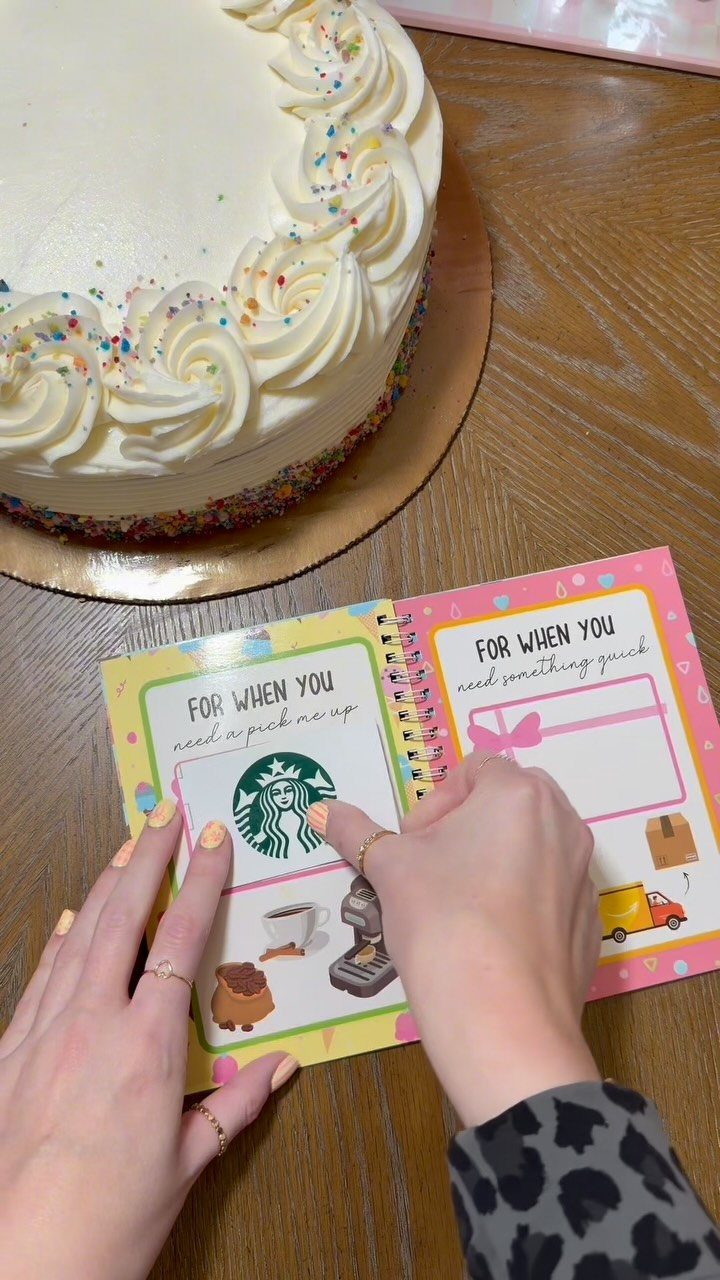 Personalized gift coupon book and a white frosted cake on a wooden table