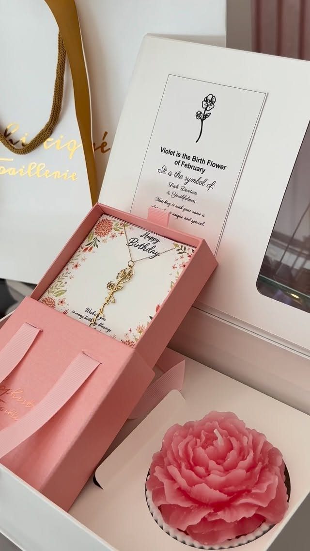 Birthday gift set with a gold necklace, pink flower candle, and greeting cards.