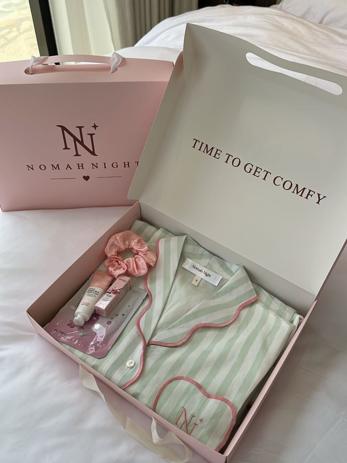 Light green striped pajamas and skincare products inside a pink gift box