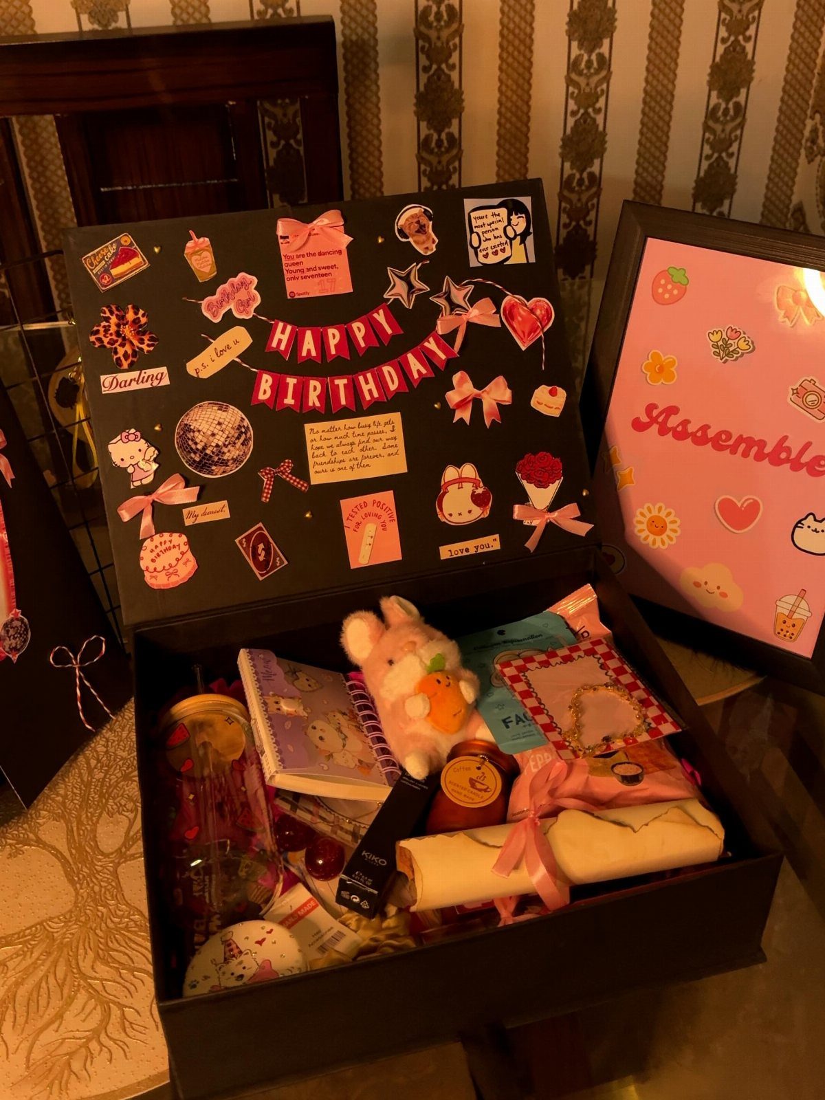 Open black birthday gift box filled with treats and decorated with stickers