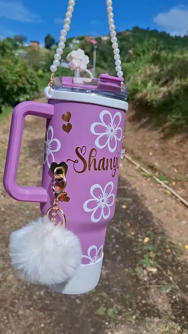 Purple personalized tumbler with gold name, white flowers, and a pearl strap.