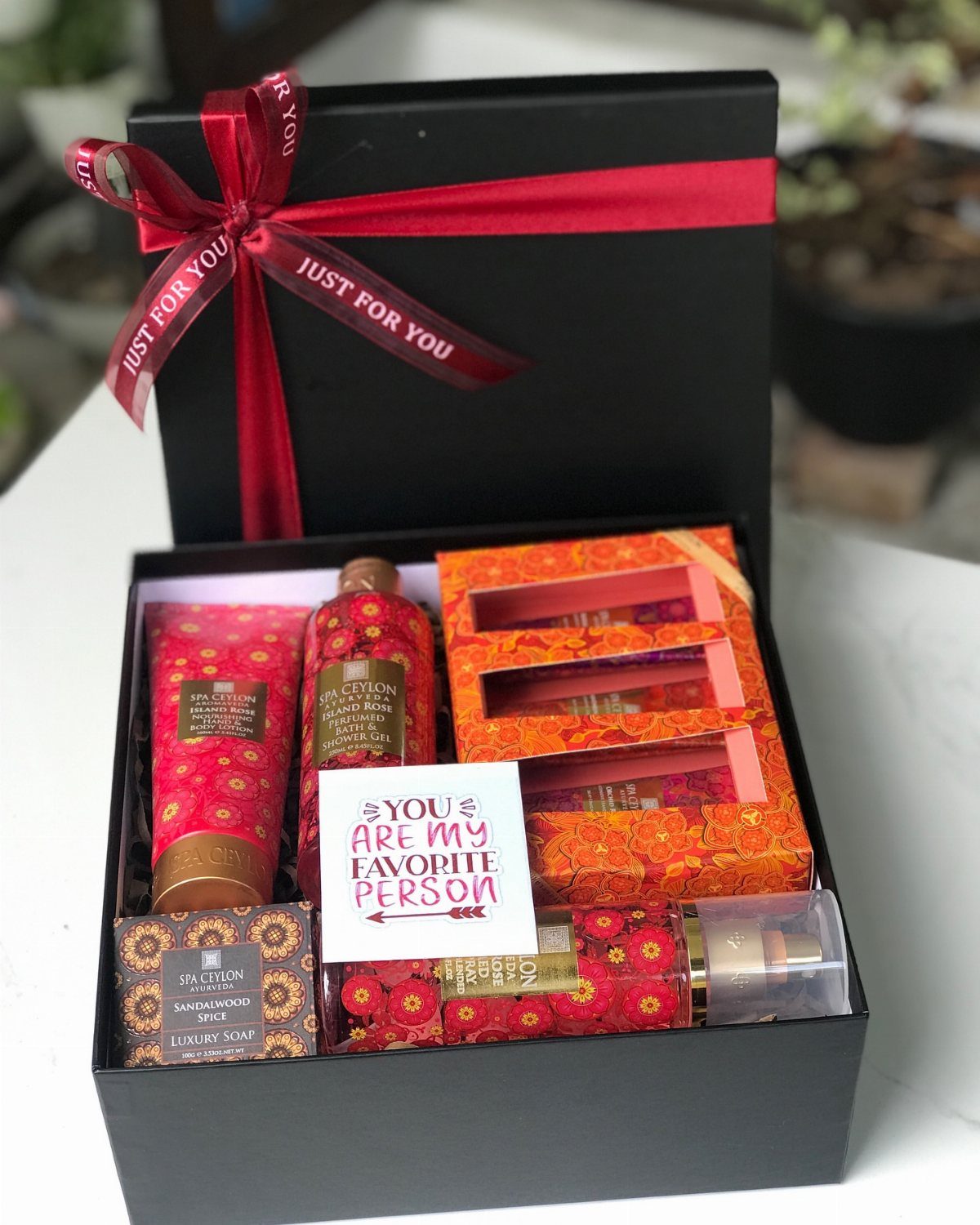 Spa gift set in a black box with red patterned bath products and ribbon.