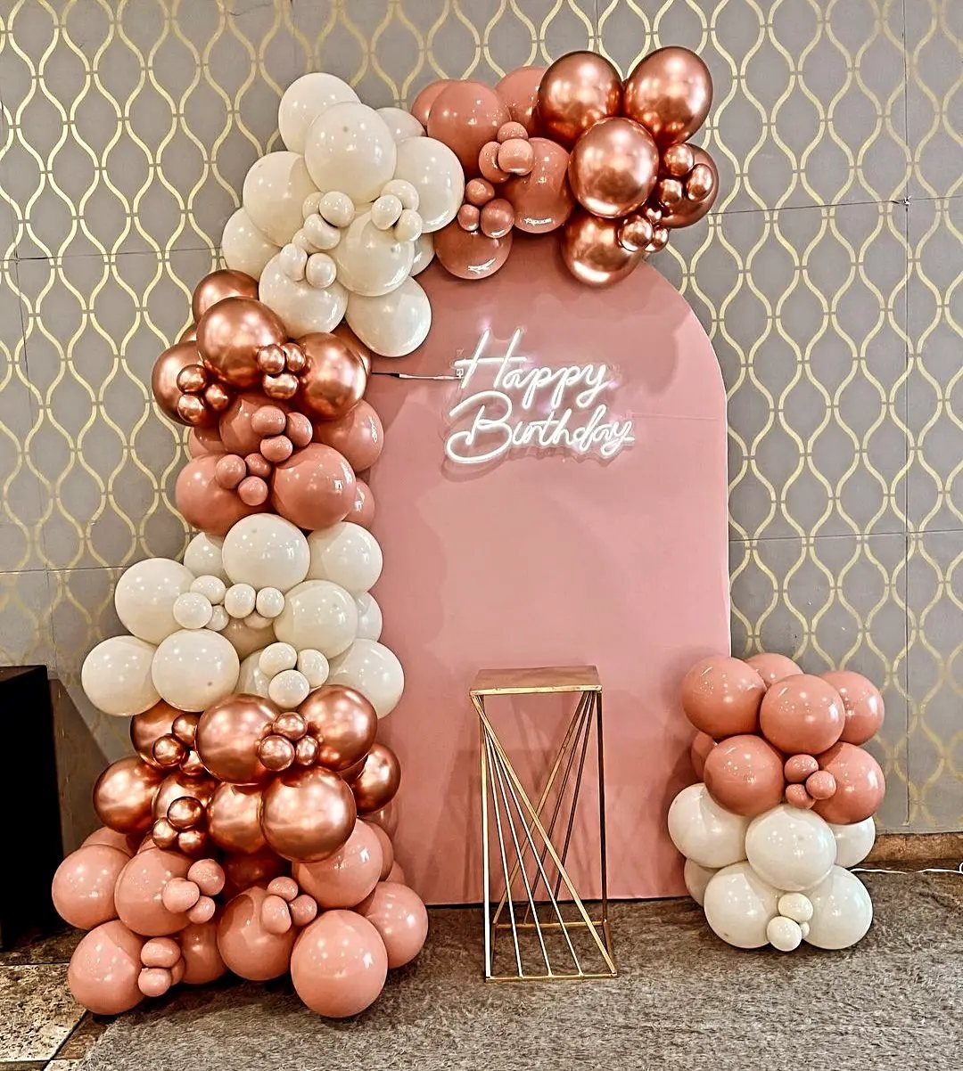 Rose gold, peach, and white balloon arch framing a pink birthday backdrop.