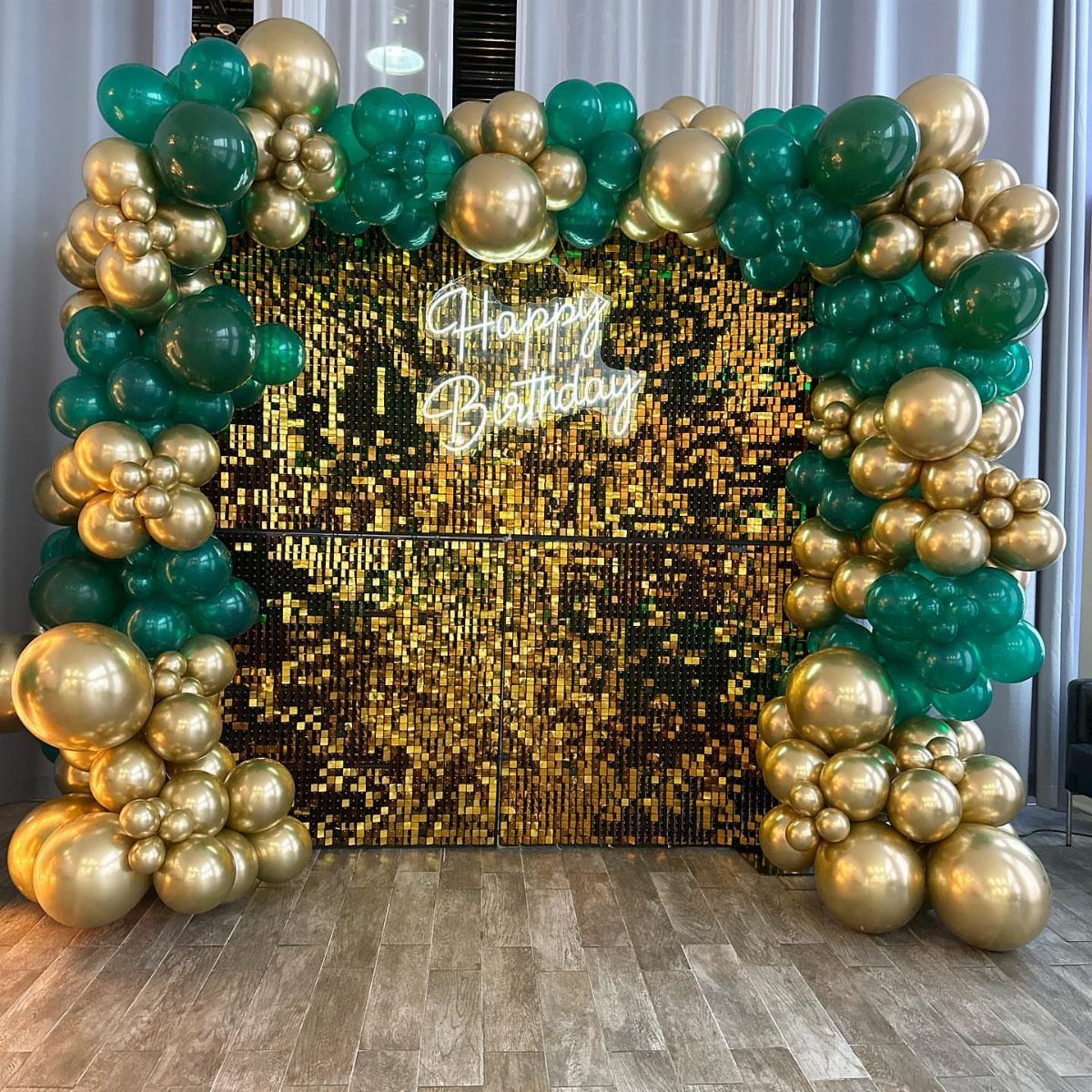 Emerald green and gold balloon arch framing a gold sequin birthday backdrop.